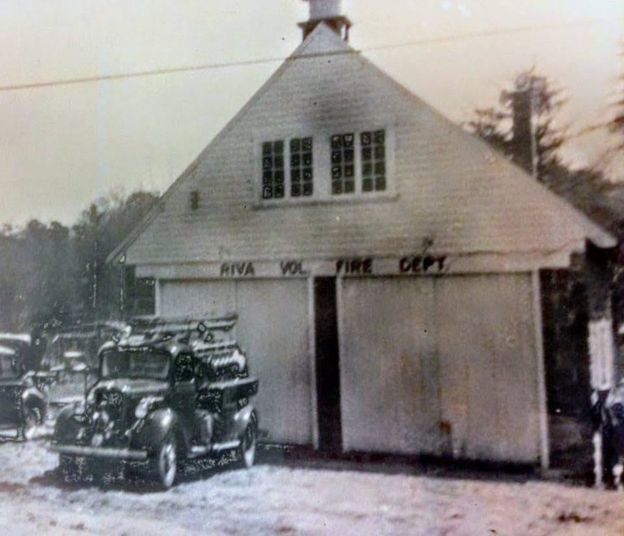 The original Riva firehouse — two bays, built by the members’ own hands, engines nosed out in the snow.