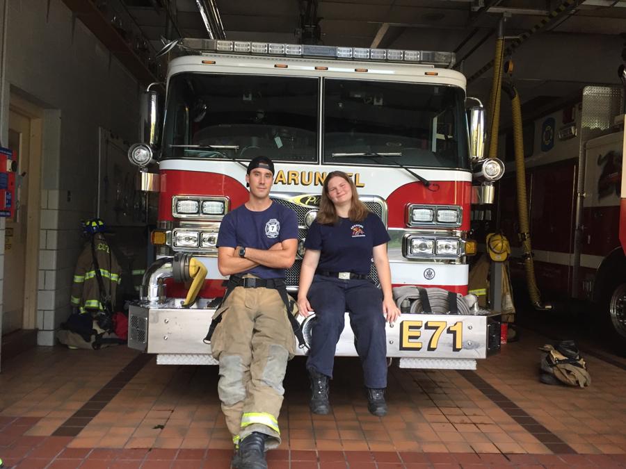 Two AVFD members sitting on the front bumper of Engine 71 in the bay