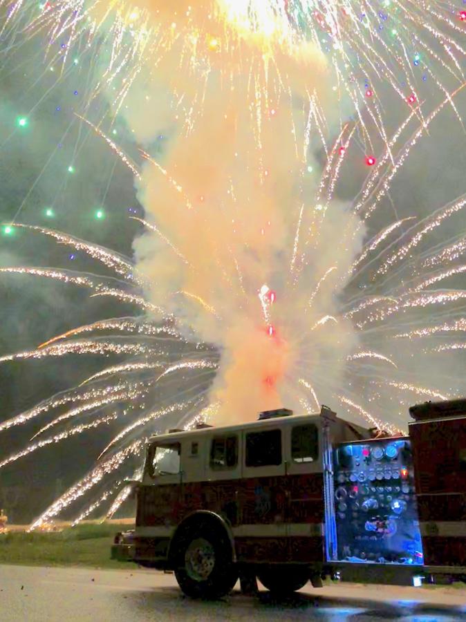 Fireworks bursting over an AVFD engine at a community event
