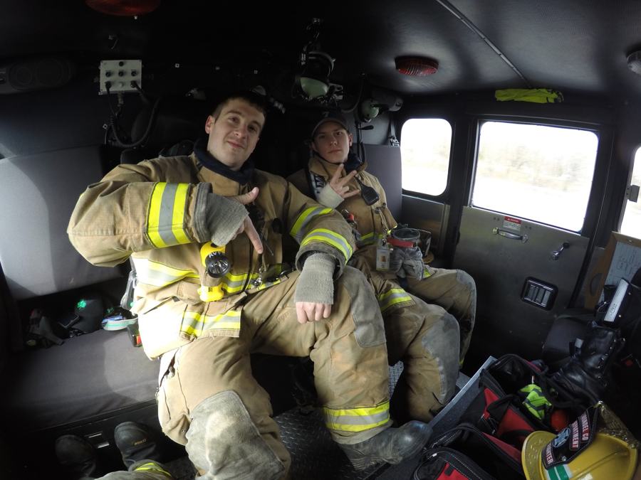 Two young AVFD firefighters in gear riding in the cab, throwing hand signs at the camera