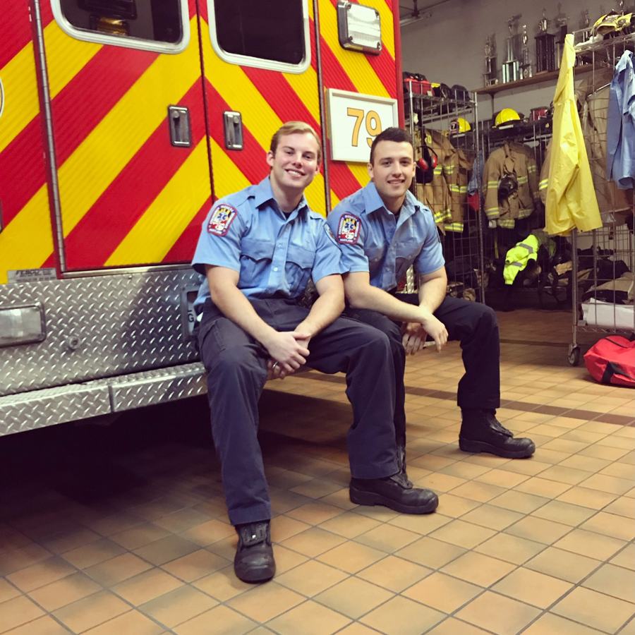 Two young members in station uniform sitting on the back step of the medic unit