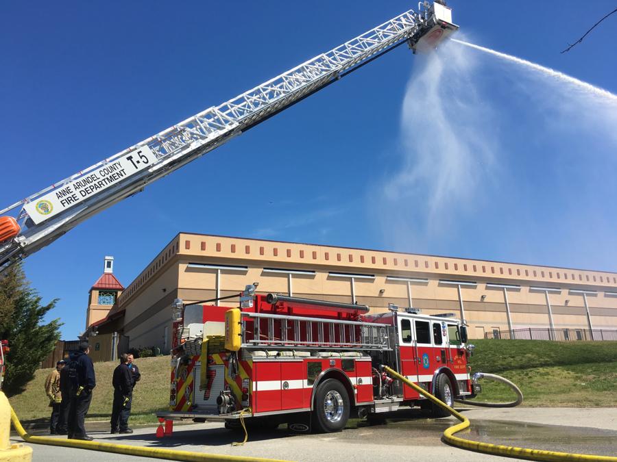 Ladder pipe flowing water over an AVFD engine during a drill