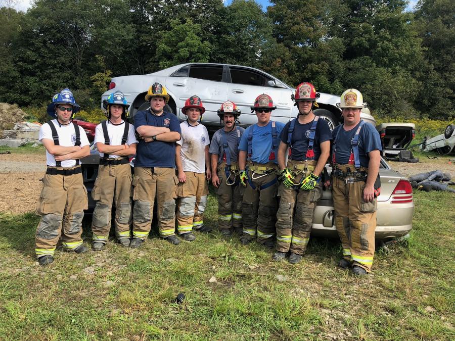 A vehicle-rescue training class posing with the car they just cut apart